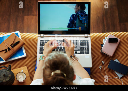 Obere Ansicht der elegante Frau sitzt auf der Couch im Wohnzimmer ansehen Film auf einem Laptop und Polish Nail. Stockfoto