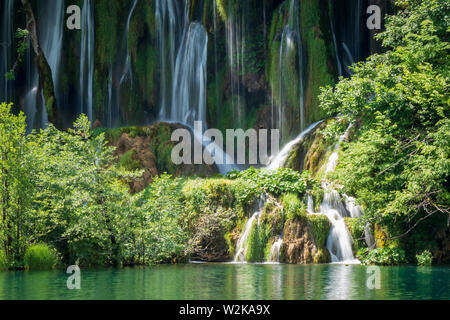 Kristallklares, reines Wasser, ausgegossen bemoosten Felsen in einem wunderschönen azurblauen See im Nationalpark Plitvicer Seen Plitvicer Seen, Kroatien Stockfoto