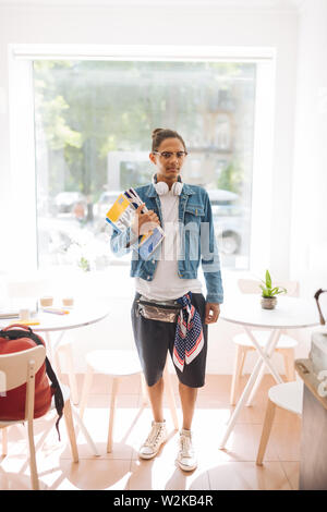 Loft Interieur. Stattliche brünette Mann hält Bücher beim Gehen Kaffee trinken nach der Universität Stockfoto