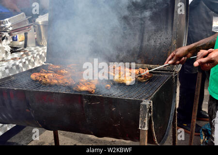 Man grillen Huhn Stücke auf Öl Grill an der Bristol St Pauls festival Drum Stockfoto