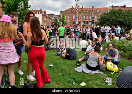 Menschen jeden Alters im Sitzen, im Stehen "Hängende über "im Summer Bristol St Pauls Karneval, Brunswick Square, Großbritannien Stockfoto