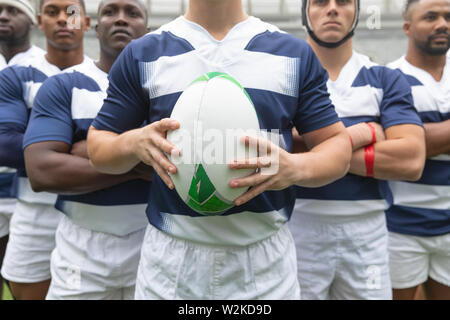Gruppe von verschiedenen männlichen Rugby Spieler zusammen mit Rugby Ball im Stadion Stockfoto