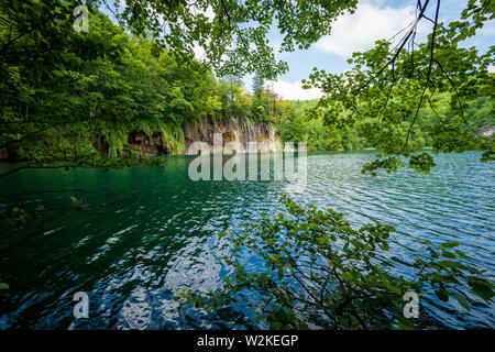 Kaskaden von Reines, frisches Wasser, ausgegossen Braun, bemoosten Felsen in einem azurblauen See im Nationalpark Plitvicer Seen Plitvicer Seen, Kroatien Stockfoto