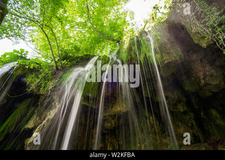 Hintergrundbeleuchtung Blick auf reines, frisches Wasser, ausgegossen Rock tief im Wald Der Nationalpark Plitvicer Seen in Kroatien Stockfoto