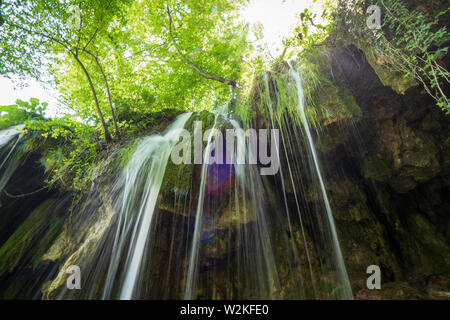 Hintergrundbeleuchtung Blick auf reines, frisches Wasser, ausgegossen Rock tief im Wald Der Nationalpark Plitvicer Seen in Kroatien Stockfoto