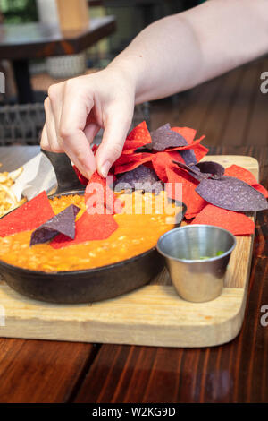 Mexikanischen Chicken Chili mit Mais und Bohnen in einer gusseisernen Pfanne, mit roten und blauen Tortilla Chips und jalapeno peppers Stockfoto