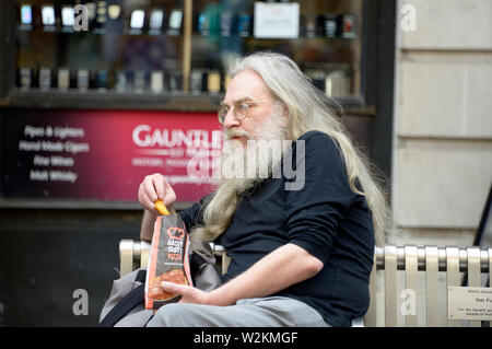 Haarige alter Mann auf einer Bank sitzen. Stockfoto