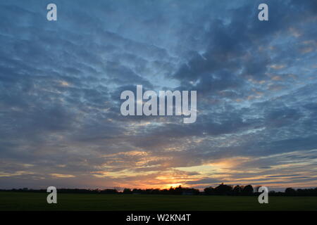 Eine Sammlung von Aufnahmen des Sonnenuntergangs über den flachen Suffolk-Feldern mit einem schönen Wolkenmuster, das sich über den Himmel ausbreitet. Stockfoto