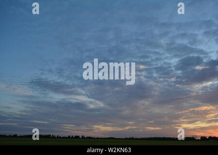 Eine Sammlung von Aufnahmen des Sonnenuntergangs über den flachen Suffolk-Feldern mit einem schönen Wolkenmuster, das sich über den Himmel ausbreitet. Stockfoto