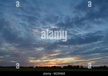 Eine Sammlung von Aufnahmen des Sonnenuntergangs über den flachen Suffolk-Feldern mit einem schönen Wolkenmuster, das sich über den Himmel ausbreitet. Stockfoto