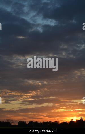 Eine Sammlung von Aufnahmen des Sonnenuntergangs über den flachen Suffolk-Feldern mit einem schönen Wolkenmuster, das sich über den Himmel ausbreitet. Stockfoto