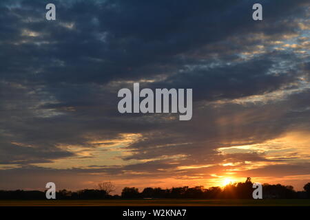 Eine Sammlung von Aufnahmen des Sonnenuntergangs über den flachen Suffolk-Feldern mit einem schönen Wolkenmuster, das sich über den Himmel ausbreitet. Stockfoto