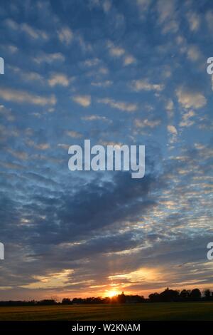 Eine Sammlung von Aufnahmen des Sonnenuntergangs über den flachen Suffolk-Feldern mit einem schönen Wolkenmuster, das sich über den Himmel ausbreitet. Stockfoto