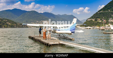 Comer see, Comer See, Italien - JUNI 2019: Panoramablick auf ein junges Paar wartet auf eine Cessna Wasserflugzeug betrieben von der Aero Club Como am Comer See. Stockfoto