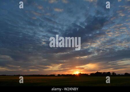 Eine Sammlung von Aufnahmen des Sonnenuntergangs über den flachen Suffolk-Feldern mit einem schönen Wolkenmuster, das sich über den Himmel ausbreitet. Stockfoto