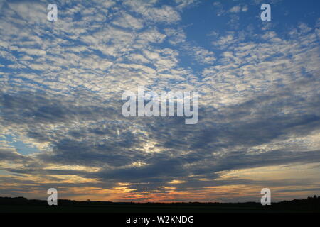 Eine Sammlung von Aufnahmen des Sonnenuntergangs über den flachen Suffolk-Feldern mit einem schönen Wolkenmuster, das sich über den Himmel ausbreitet. Stockfoto