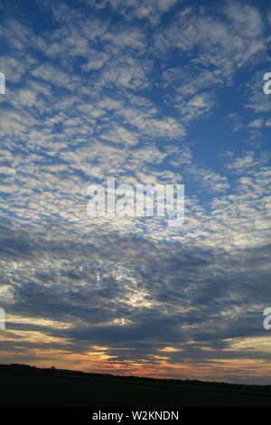Eine Sammlung von Aufnahmen des Sonnenuntergangs über den flachen Suffolk-Feldern mit einem schönen Wolkenmuster, das sich über den Himmel ausbreitet. Stockfoto