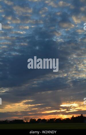 Eine Sammlung von Aufnahmen des Sonnenuntergangs über den flachen Suffolk-Feldern mit einem schönen Wolkenmuster, das sich über den Himmel ausbreitet. Stockfoto