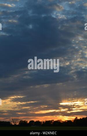 Eine Sammlung von Aufnahmen des Sonnenuntergangs über den flachen Suffolk-Feldern mit einem schönen Wolkenmuster, das sich über den Himmel ausbreitet. Stockfoto