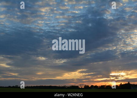 Eine Sammlung von Aufnahmen des Sonnenuntergangs über den flachen Suffolk-Feldern mit einem schönen Wolkenmuster, das sich über den Himmel ausbreitet. Stockfoto