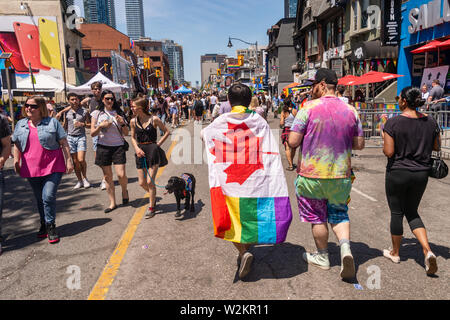 Toronto, CA - 23. Juni 2019: ein Mann mit einem Regenbogen gay Flagge auf seinem Rücken wird Toronto Gay Pride Parade. Stockfoto