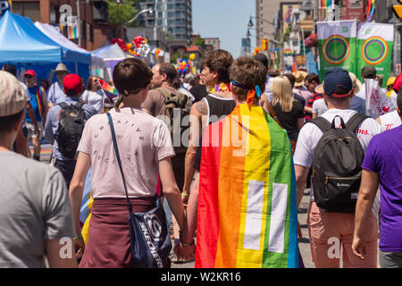 Toronto, CA - 23. Juni 2019: ein Mann mit einem Regenbogen gay Flagge auf seinem Rücken wird Toronto Gay Pride Parade. Stockfoto