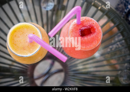 Frisch gemischt Smoothies in verschiedenen Farben und Geschmacksrichtungen, die in Gläsern. Frischer Saft Gelb, Rot. Saft trinken im Freien. Sommer Getränke für Kinder Stockfoto