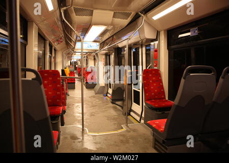 Innen leere moderne Straßenbahn mit roten Sitzen. Nacht Stockfoto