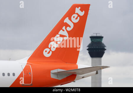 Die heckflosse eines Easyjet airliner entlang der Start- und Landebahn vor dem Kontrollturm am Flughafen Manchester rollen. Stockfoto