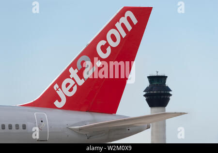 Die heckflosse eines Jet 2 Airliner entlang der Start- und Landebahn vor dem Kontrollturm am Flughafen Manchester rollen. Stockfoto