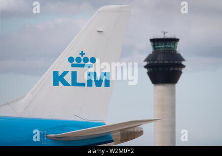 Die heckflosse eines KLM Airliner entlang der Start- und Landebahn vor dem Kontrollturm am Flughafen Manchester rollen. Stockfoto