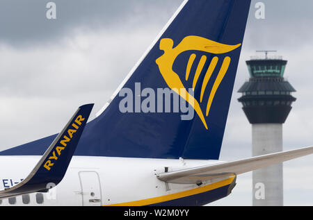 Die heckflosse eines Ryanair airliner entlang der Start- und Landebahn vor dem Kontrollturm am Flughafen Manchester rollen. Stockfoto