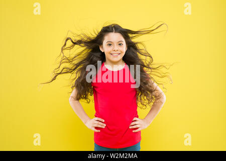 Kind süß Gesicht mit adorable curly Frisur. Kleines Mädchen lange Haare wachsen. Teen Mode Modell. Unterschied entdecken. Styling lockiges Haar. Friseur Tipp. Kind Mädchen lange gesund glänzendes Haar. Perfekte locken. Stockfoto