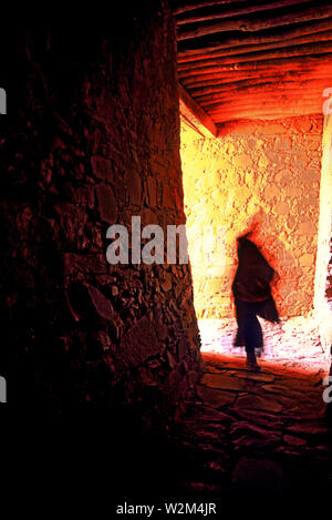 Obwohl viele Klöster zerstört worden sind, die Tibeter immer noch diejenigen, die in ihrem ursprünglichen Zustand belassen. Ein Mönch Spaziergänge durch den Stein innere Passage von einem Kloster. Stockfoto