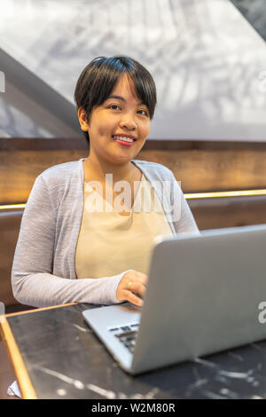 Portrait der asiatischen Frau in kurzen Haaren Arbeiten am Laptop Stockfoto