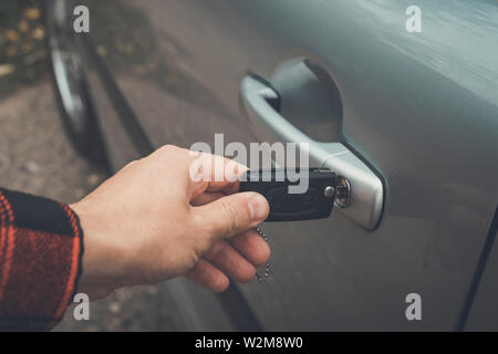 Nahaufnahme einer männlichen Hand Öffnen der Kabinentür. Person fügt die Taste der Fernbedienung, die in der Bohrung eines Fahrzeugs. Öffnen der automatischen Tür mit Schlüssel Stockfoto