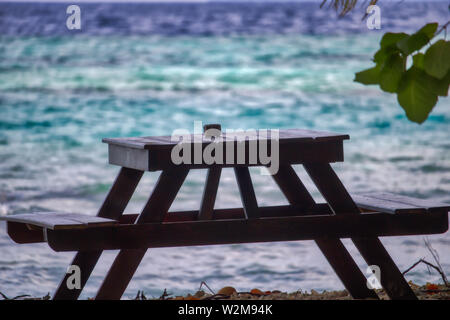 Dieses einzigartige Foto zeigt einen hölzernen Tisch, ist ein romantischer Ort am Strand der Malediven Stockfoto