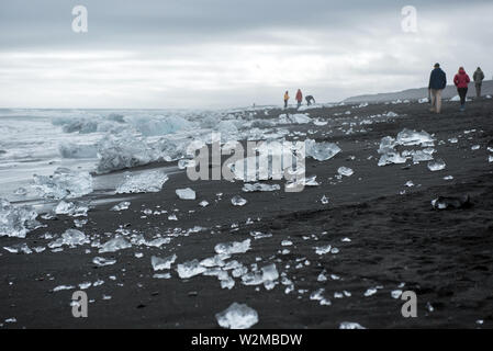 DIAMOND BEACH, JOKULSARLON, ISLAND - 22. MAI 2019: Touristen bewundern und Fotografieren der schmelzenden Eisbergen auf dem Atlantik Küste in Jokulsarlo Stockfoto