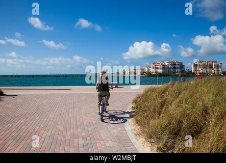 Model Released weibliche Touristen, ein Leihfahrrad in Miami's South Point mit Fisher Island über das Wasser. Stockfoto