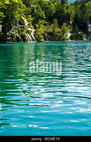 Rauschende Wasserfälle, die natürliche Hindernisse in den glasklaren und azurblauen See Milanovac im Nationalpark Plitvicer Seen, Kroatien Stockfoto