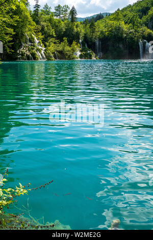 Rauschende Wasserfälle, die natürliche Hindernisse in den glasklaren und azurblauen See Milanovac im Nationalpark Plitvicer Seen, Kroatien Stockfoto