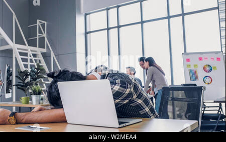 Kreative Designer fallen asleepy während hart arbeiten mit Laptop im modernen Büro. Arbeitsplatz lifesyle Konzept Stockfoto