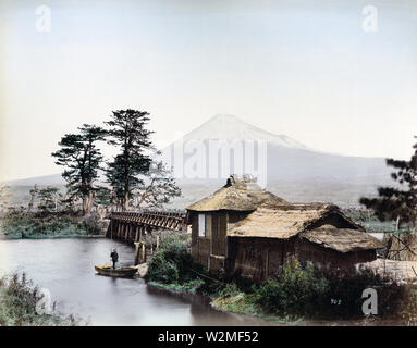 [1880s Japan - Kawaibashi Brücke auf der Tokaido] - Kawaibashi Brücke überspannt den Fluss in der Nähe von Taganoura Numakawa der Tokaido. Im Vordergrund ist ein Gebäude mit Strohdach, daneben ist ein kleines Wharf, wo ein Mann in ein kleines Holzboot steht. Im Hintergrund Mt. Fuji gesehen werden kann. Die Numakawa fließt von Ukishima Teich in Richtung Tagonoura. Vor der Brücke während des Kanbun-Ära (1661-1673) erbaut wurde, Menschen gekreuzt dieser Standort mit der Fähre. Über die Brücke Strommasten kann gesehen werden, dass dieses Bild in den 1880er Jahren aufgenommen wurde. 19 Vintage albumen Foto Stockfoto