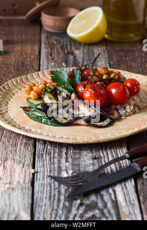 Gesunde vegane Mahlzeit. Veggie Salat mit gegrilltem Gemüse, Tomaten, Auberginen, Zucchini, Quinoa, knusprige knusprig gerösteten Kichererbsen auf ländlichen cerami Stockfoto