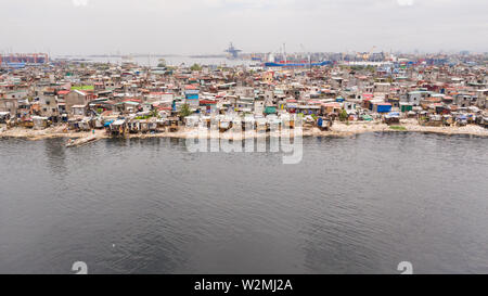 Slums in Manila in der Nähe des Hafens. Die Häuser der armen Bewohner. Eine Menge Müll im Wasser, auf den Philippinen, in der Ansicht von oben. Stockfoto