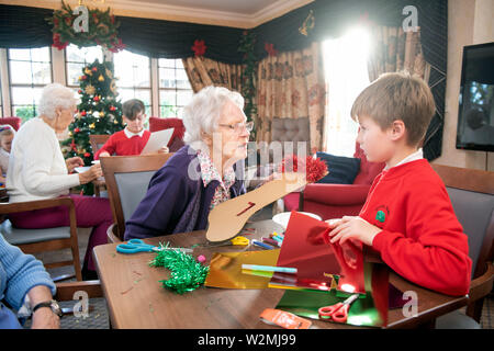 Schulkinder in der Bristol besuchen Pflegeeinrichtungen zu Weihnachten Dekorationen machen mit Bewohnern in einem Programm organisiert von der Nächstenliebe lebendig Tätigkeit Stockfoto