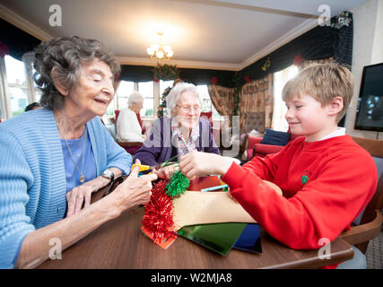 Schulkinder in der Bristol besuchen Pflegeeinrichtungen zu Weihnachten Dekorationen machen mit Bewohnern in einem Programm organisiert von der Nächstenliebe lebendig Tätigkeit Stockfoto