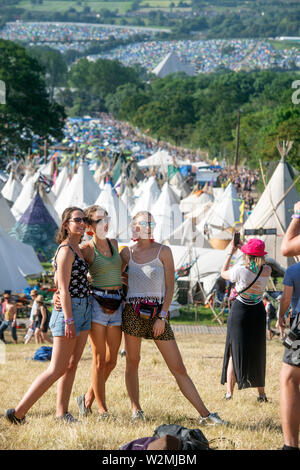 Festival - goers​ posieren für ein Foto über dem Tipidorf an Glastonbury 2019 Stockfoto