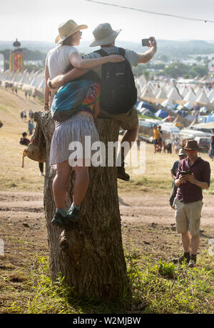 Festivalbesucher posieren für ein Foto über dem Tipidorf an Glastonbury 2019 Stockfoto