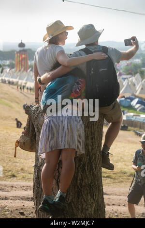 Festivalbesucher posieren für ein Foto über dem Tipidorf an Glastonbury 2019 Stockfoto